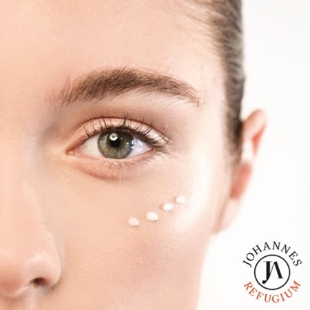 Symbolbild mit Nahaufnahme eines weiblichen Gesichts mit Blick auf das Auge und unter dem Auge eine Anwendung von einem Produkt